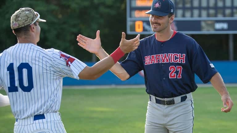 Harwich Mariners pitcher Joe Savino, right, greets Chatham Anglers outfielder...