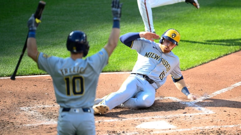 Milwaukee Brewers' Oliver Dunn (15) slides home to score on...