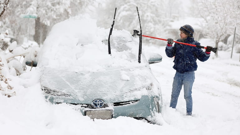 Cathy Morgan-Mace cleans snow and ice off her family's car...