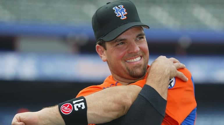 Mike Piazza smiles as he stretches with the Mets during...