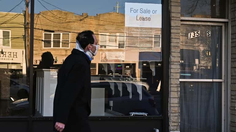 A person passes a storefront on Wellwood Avenue in Lindenhurst...