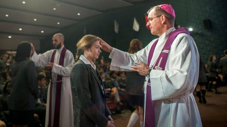 Bishop John Barres administers ashes at a Mass on Ash...