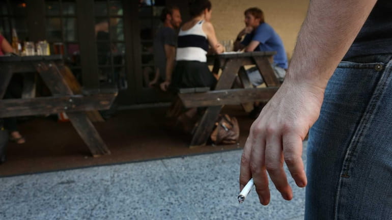 A customer stands away from a Manhattan restaurant to smoke...