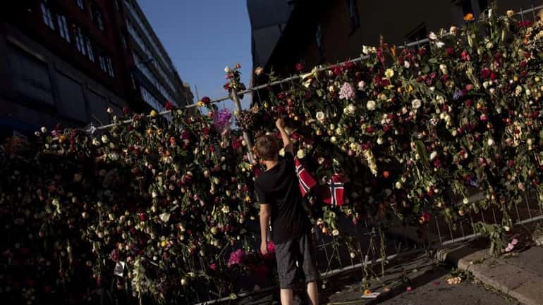 A boy places a rose on a fence surrounding the...