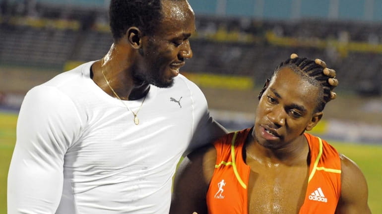 World champion Yohan Blake, right, is congratulated by world-record holder...