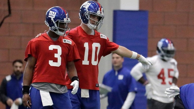 Giants quarterback Eli Manning instructs quarterback Geno Smith, left, during...