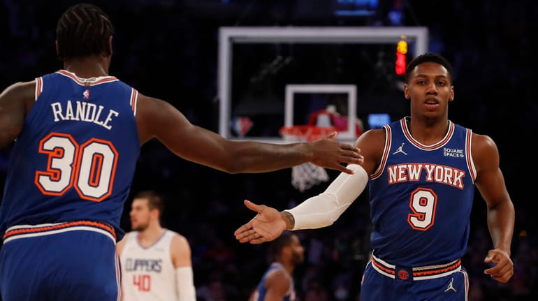 New York Knicks' RJ Barrett, center, goes up for a...