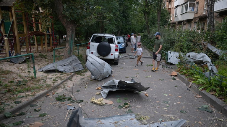 Local residents pass by debris in Kyiv, Ukraine, Wednesday, Aug....