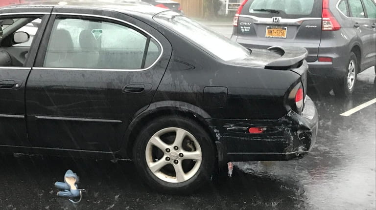 A black Nissan with damage in the parking lot across...