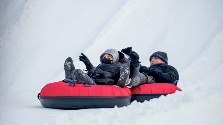 A pair of snow tubers reaches the bottom of the...