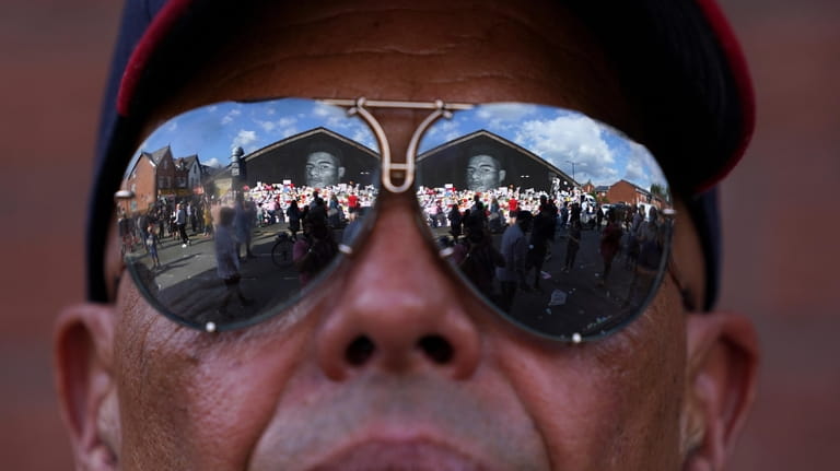 People are reflected in a man's sunglasses looking at the...