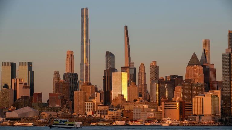 Light from the setting sun reflects off the buildings in...