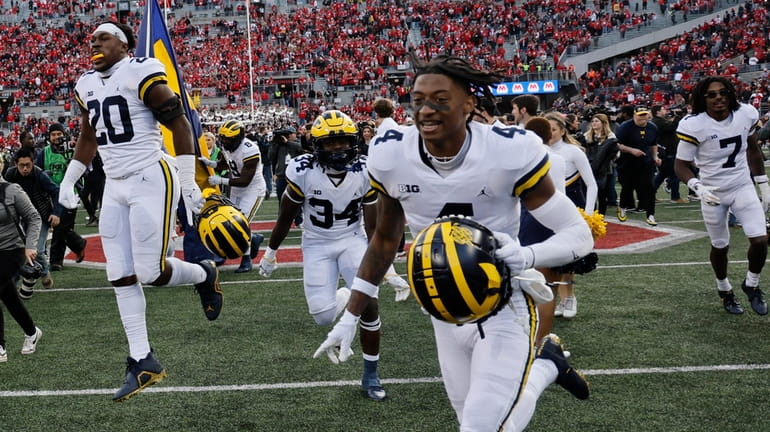 Michigan players celebrate their win over Ohio State after an...