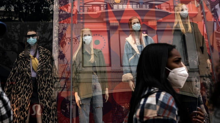 A shopper walks Monday past mannequins donning face masks in...