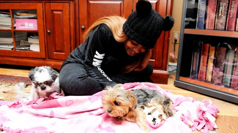 Dominique Baptiste, 24, comforts Zoey, and her four puppies inside...