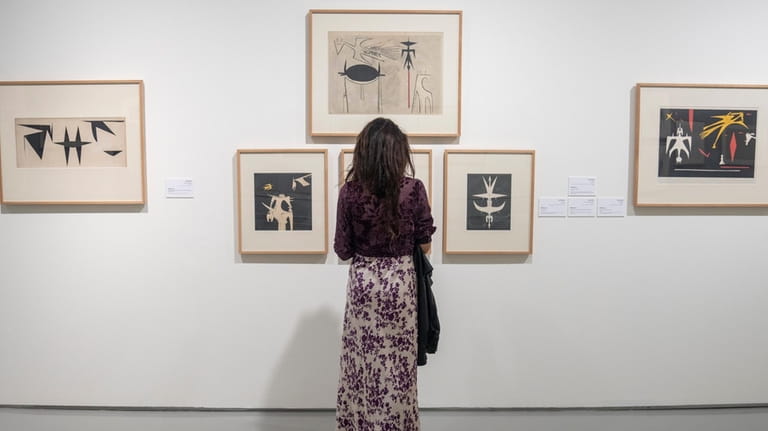 A visitor observes artwork by Afro-Cuban painter Wifredo Lam at...