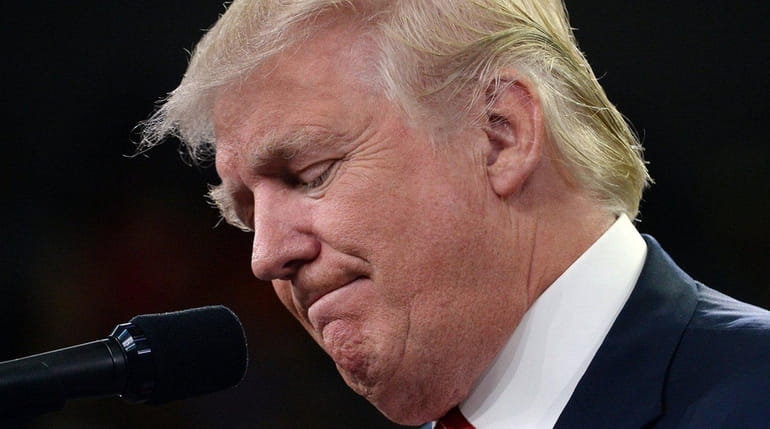 Republican presidential candidate Donald Trump grimaces as he makes remarks...