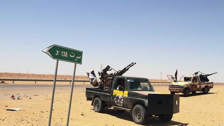 Libyan rebel vehicles with mounted missile launchers are parked next...
