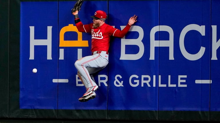 Cincinnati Reds right fielder Jake Fraley collides with the wall...