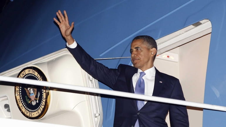 President Barack Obama waves as he boards Air Force One...