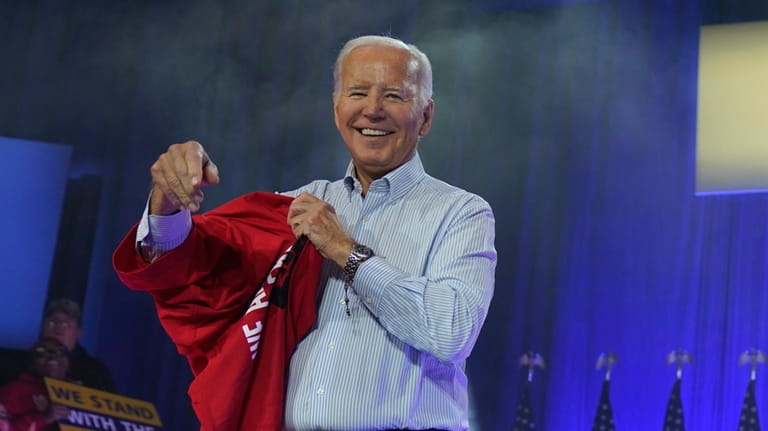 President Joe Biden puts on a UAW Local 1268 shirt...