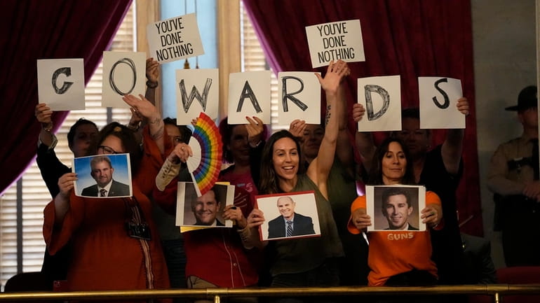 People in the gallery hold signs over the House chamber...