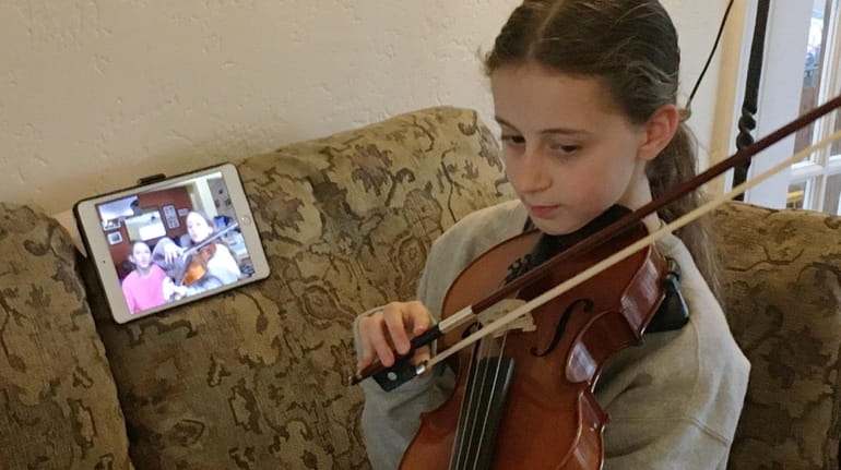Kelsey Langbart, 12, of Lido Beach, practices music virtually with...
