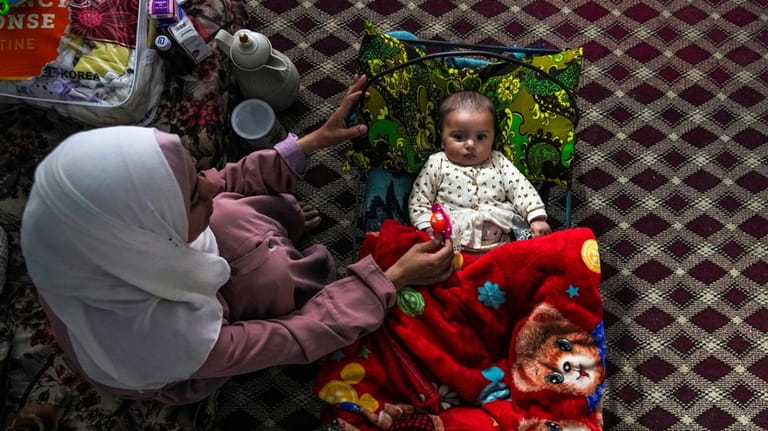 Rola Saqer sits beside her baby Massa Mohammad Zaqout in...