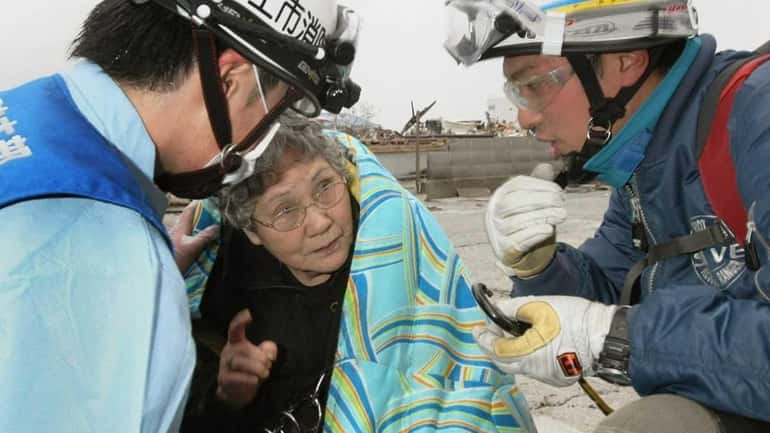 Sumi Abe, 80, speaks to firefighters after being rescued in...