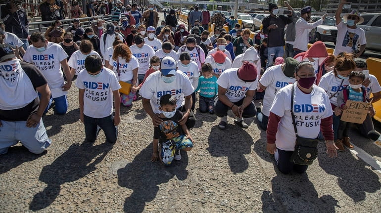 Migrants wearing T-shirts that read "Biden please let us in"...