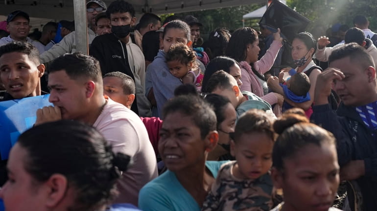 Venezuelan migrants and their children wait to enter a temporary...