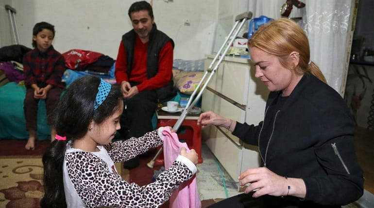 Lindsay Lohan, right, spends time with a family of Syrian...