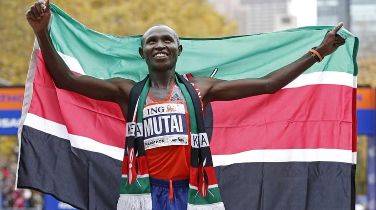 Geoffrey Mutai of Kenya holds the Kenyan flag after winning...