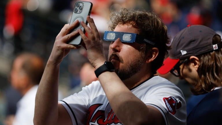 A Cleveland Guardians fan uses special glasses to take a...