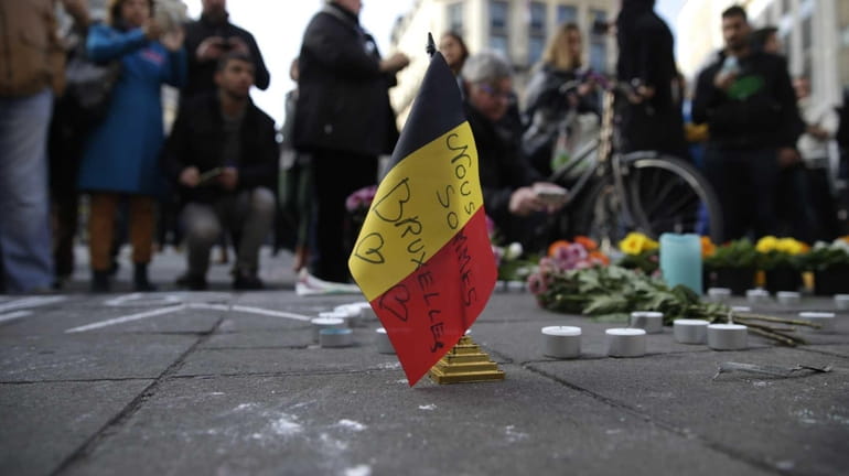 A Belgian flag reading "We are all Brussels" stands at...