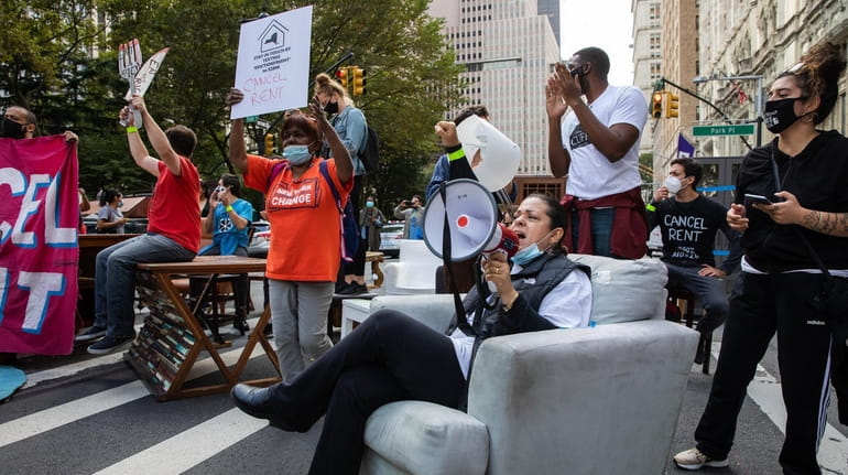 Demonstrators hold signs and sit on furniture placed in the...