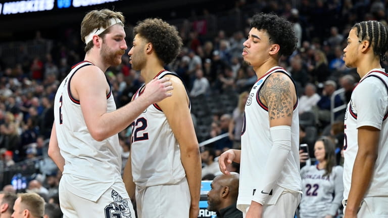 Gonzaga forward Drew Timme, left, hugs with teammates while checking...