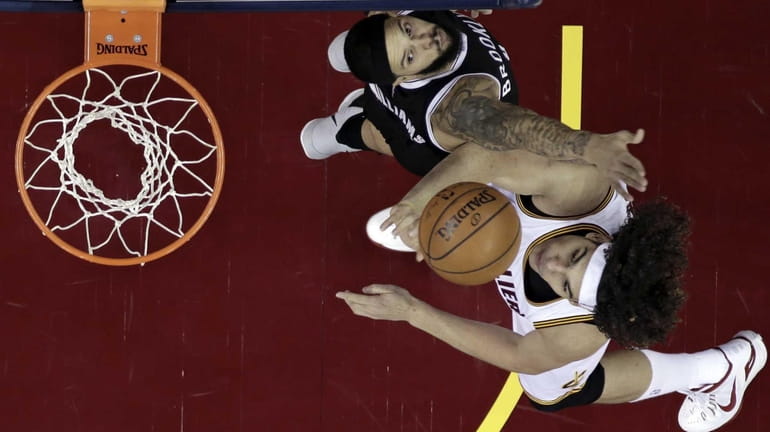 Cleveland Cavaliers' Anderson Varejao, bottom, from Brazil, drives to the...