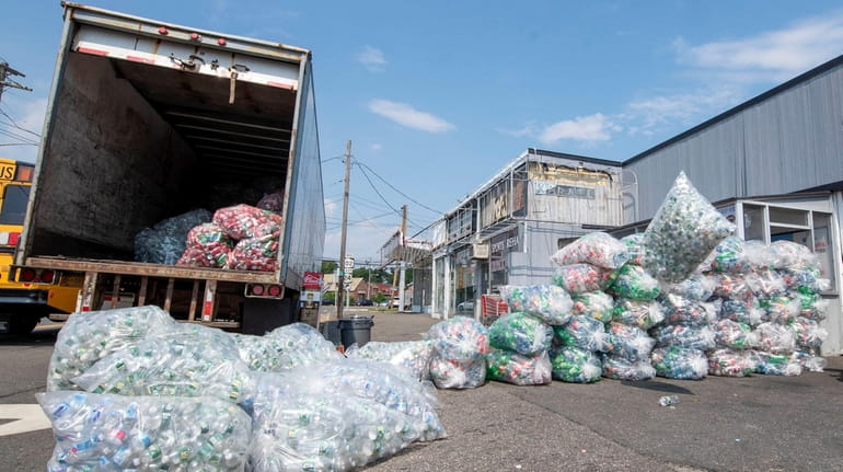 Bags of plastic bottles are loaded onto a truck at...