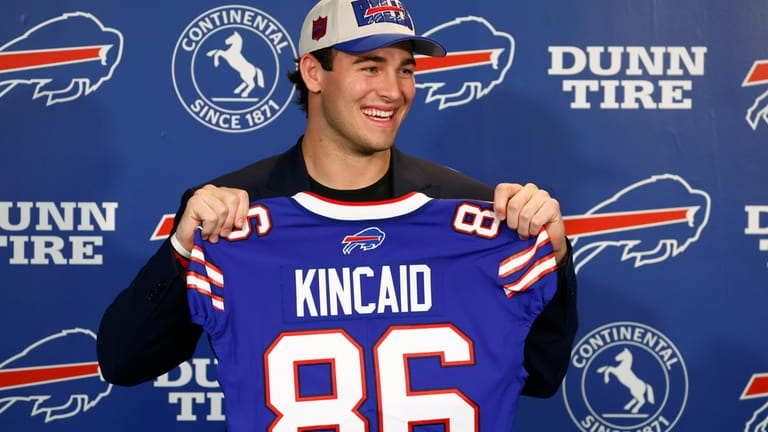 Buffalo Bills first-round draft pick Dalton Kincaid holds up a...