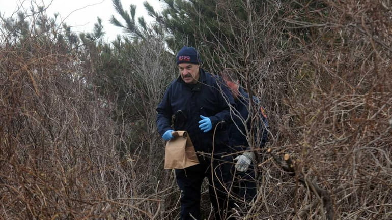 Nassau County police crime scene investigators remove a bag of...