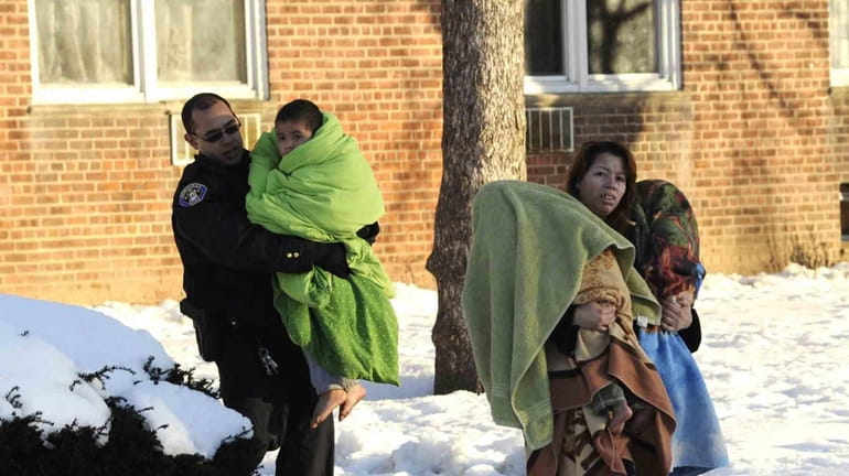 A rescuer helps residents escape a Hempstead apartment building where...