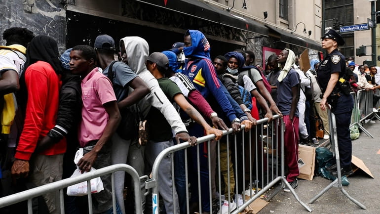 Migrants bused in from Southern states line up on a...