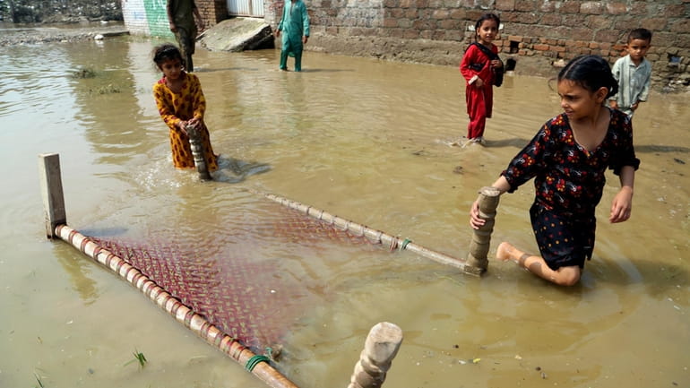Children salvage a cot from their home, in Charsadda, Pakistan,...