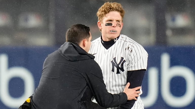 A trainer checks on Yankees centerfielder Harrison Bader after he...