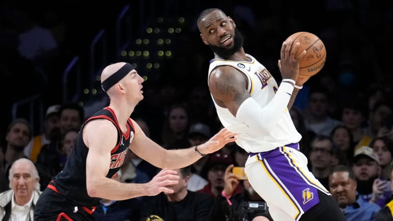 Los Angeles Lakers forward LeBron James, right, is defended by...