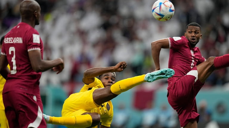 Ecuador's Felix Torres, center, duels for the ball with Qatar's...