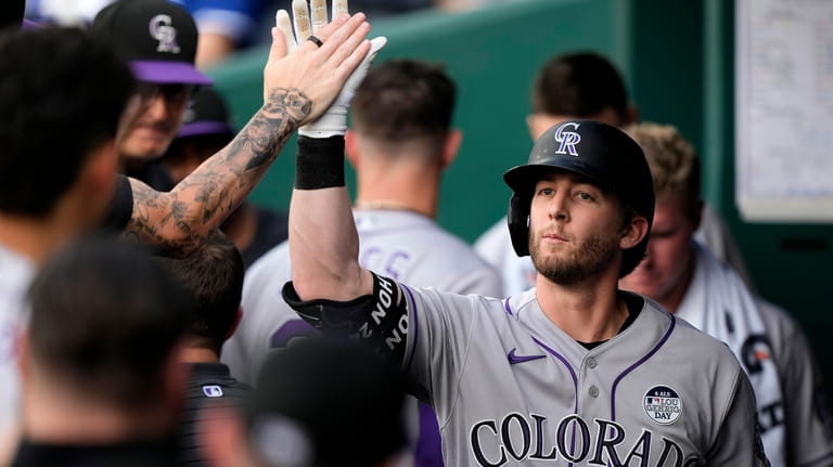 Colorado Rockies' Ryan McMahon celebrates in the dugout after hitting...