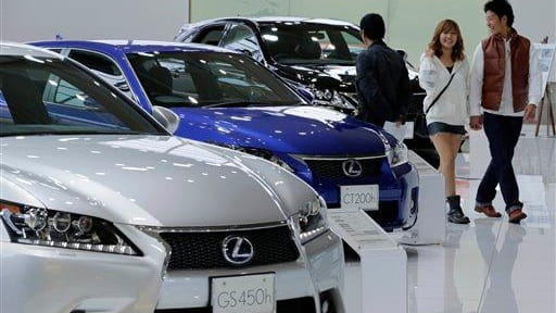 A couple walk by Lexus models displayed at a Toyota...