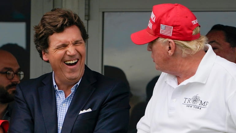 Tucker Carlson, left, and former President Donald Trump, right, react...